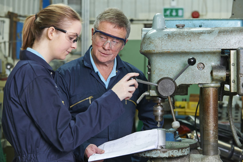 49380162 - engineer showing apprentice how to use drill in factory